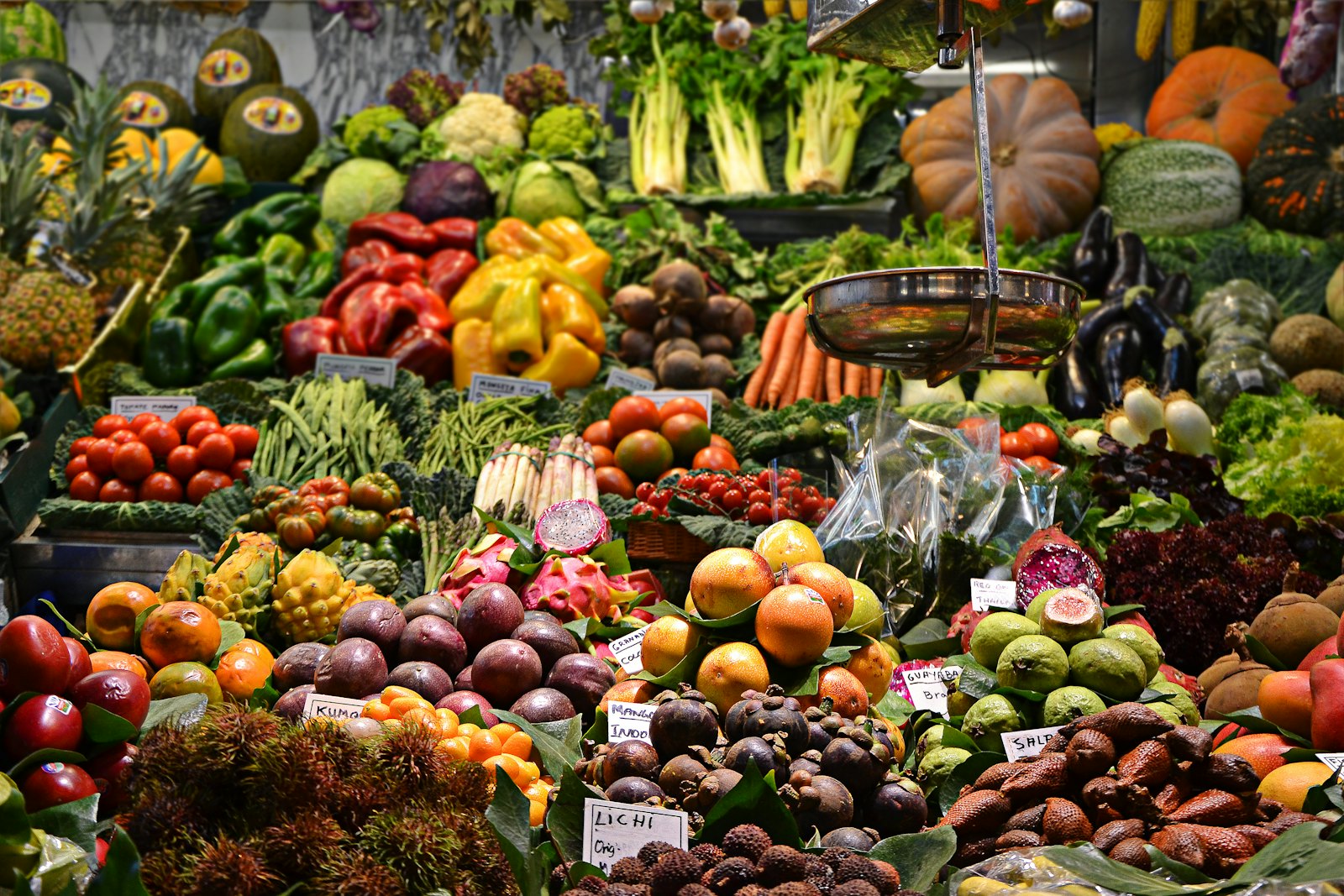 Stacked oranges and dark green leafy vegetables at a Portuguese market stall